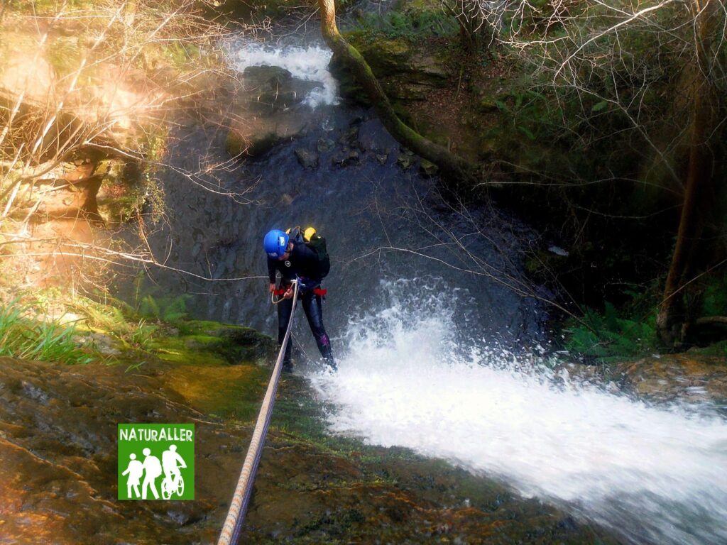 Persona practicando barranquismo en cascada con equipo.