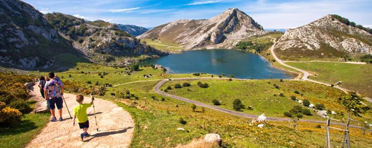 Lago en Asturias con sendero y montañas verdes.