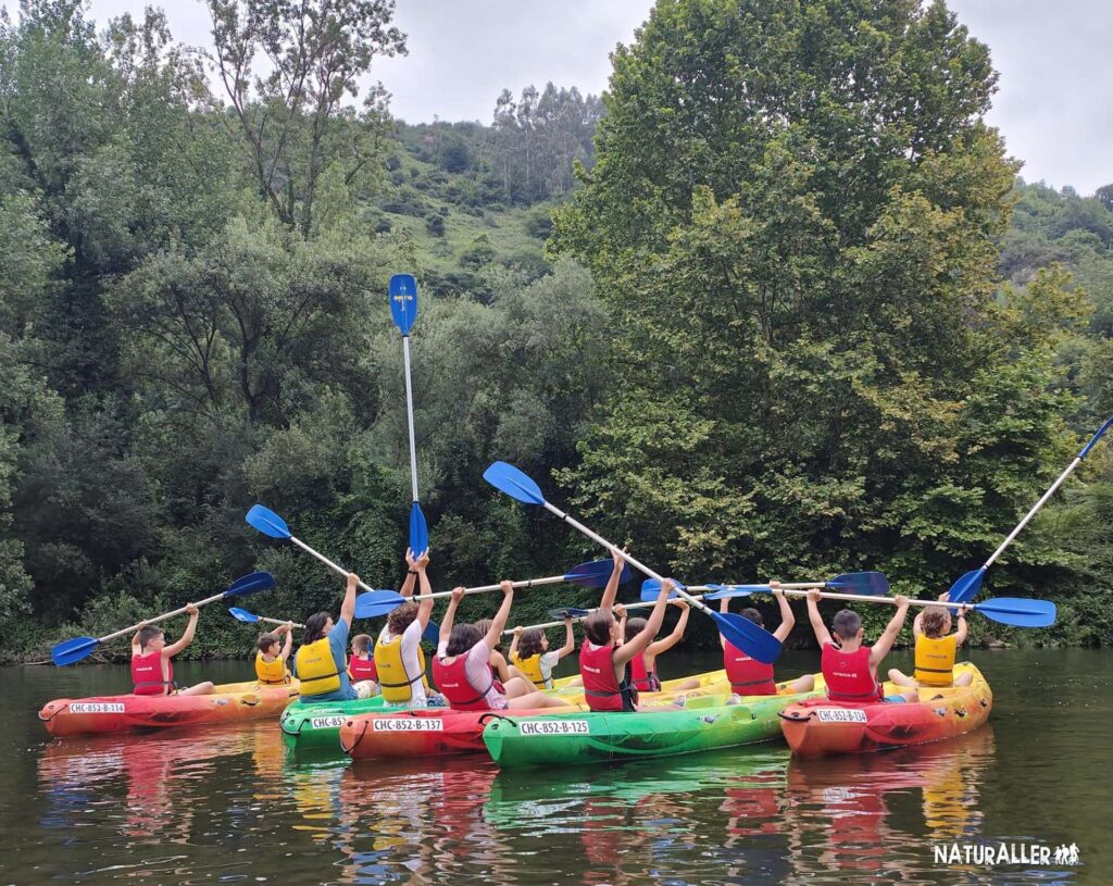 Grupo de personas en kayaks de colores brillantes, remando en un río rodeado de vegetación exuberante. Ideal para actividades al aire libre y deportes acuáticos.