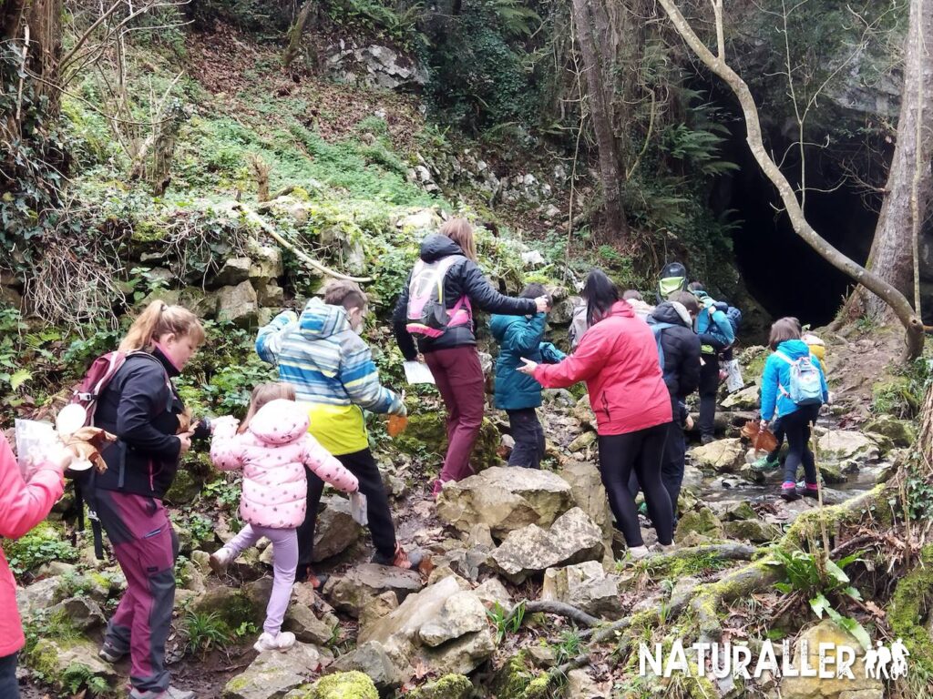 Grupo explorando entrada de cueva en el bosque.